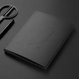 Black notebook and scissors on a dark gray background