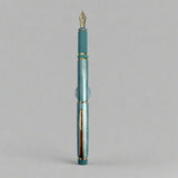 Green fountain pen with gold accents on a light blue background