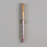 Fountain pen with purple and gold accents on a light beige background