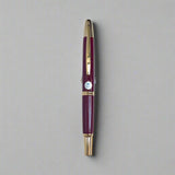 Maroon pen with gold accents on a light blue background