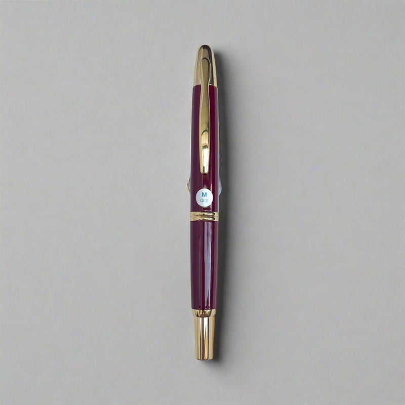 Maroon pen with gold accents on a light blue background