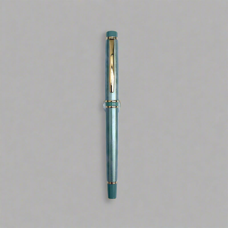 Green pen with gold accents on a light blue background