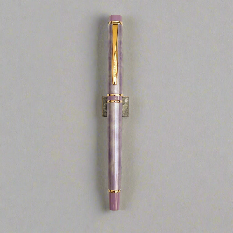 Fountain pen with purple and gold accents on a light beige background