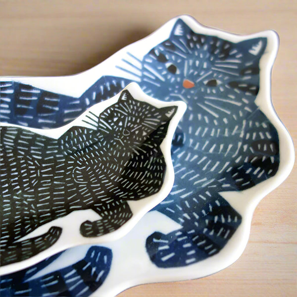 Decorative plate with black cat design on a wooden surface